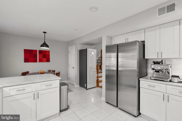 kitchen with visible vents, white cabinets, decorative light fixtures, freestanding refrigerator, and backsplash
