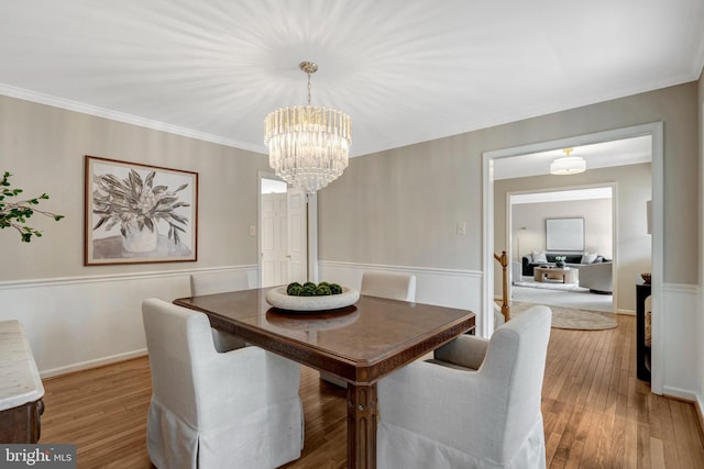 dining room with light wood-type flooring, crown molding, baseboards, and an inviting chandelier