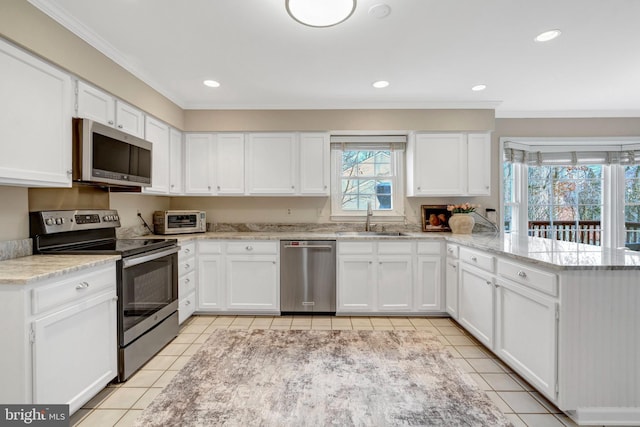 kitchen featuring light tile patterned floors, stainless steel appliances, white cabinetry, a sink, and a peninsula