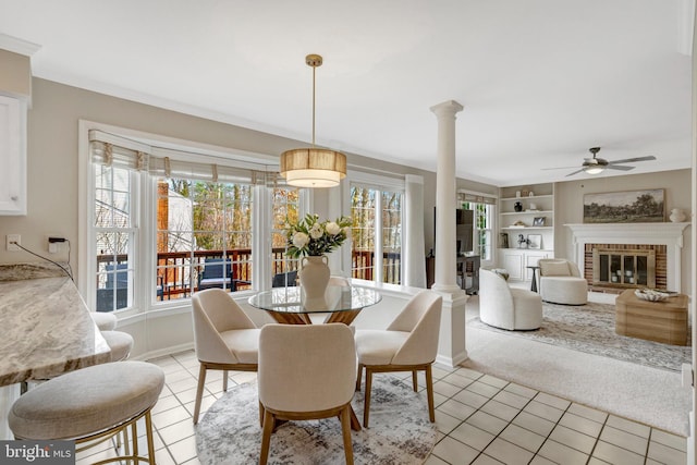 dining area featuring light colored carpet, ornate columns, a brick fireplace, built in shelves, and light tile patterned flooring