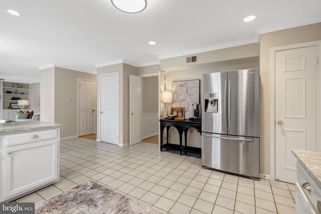 kitchen with crown molding, stainless steel refrigerator with ice dispenser, light tile patterned floors, visible vents, and white cabinets