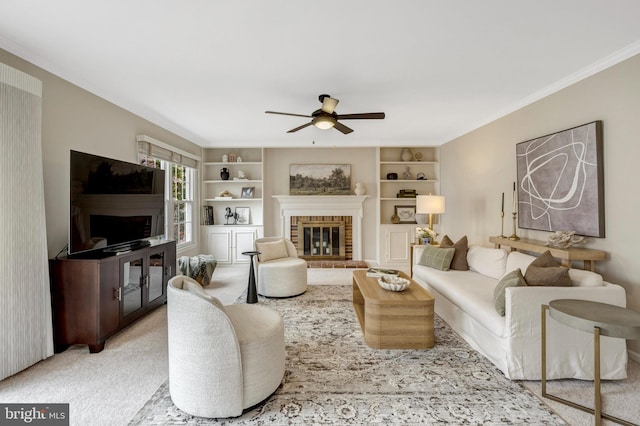 living room featuring crown molding, light colored carpet, a fireplace, and a ceiling fan