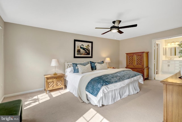 bedroom with baseboards, connected bathroom, a ceiling fan, and light colored carpet