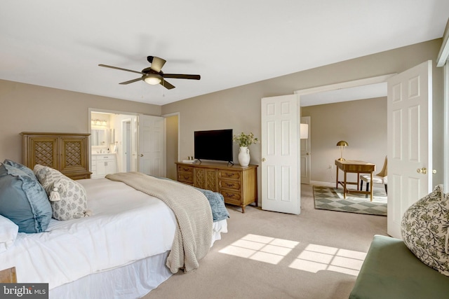 bedroom with light carpet, ensuite bath, and a ceiling fan