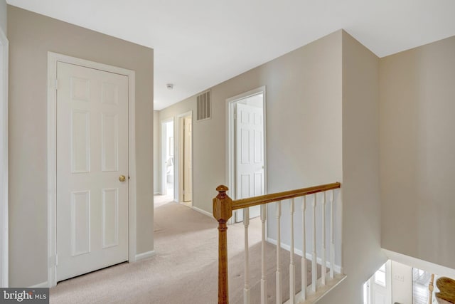 corridor with baseboards, carpet flooring, visible vents, and an upstairs landing