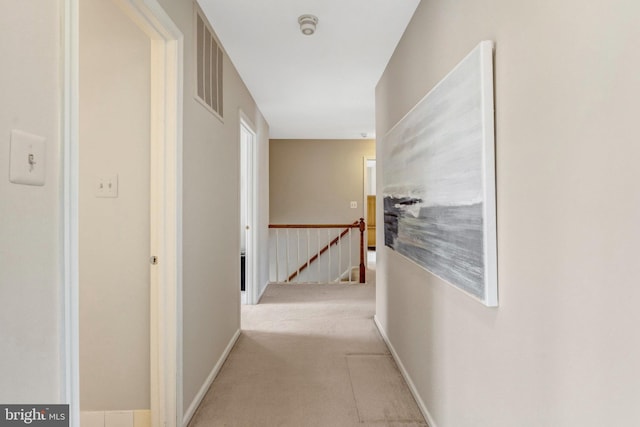 corridor with visible vents, carpet floors, and an upstairs landing