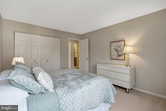 bedroom with baseboards, a closet, and light colored carpet