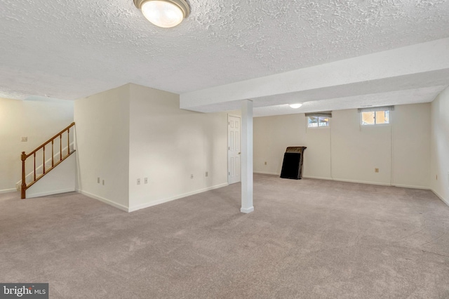 below grade area with carpet flooring, stairway, baseboards, and a textured ceiling