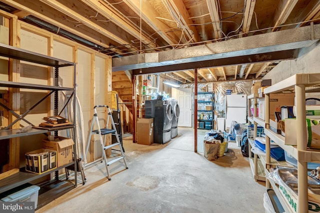 unfinished basement featuring separate washer and dryer and freestanding refrigerator