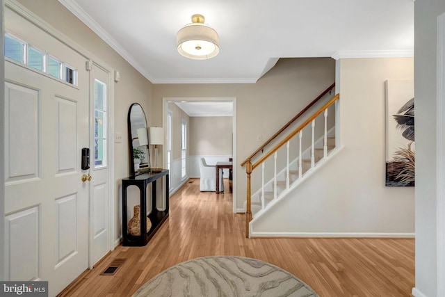 entrance foyer with wood finished floors, visible vents, baseboards, stairway, and crown molding