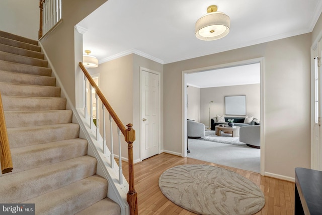 entrance foyer featuring light wood-type flooring, baseboards, and crown molding