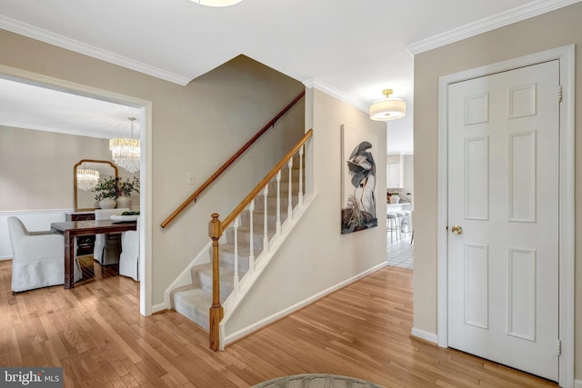 stairs with ornamental molding, baseboards, an inviting chandelier, and wood finished floors