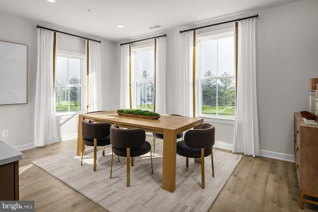 dining space with light wood finished floors, visible vents, and baseboards