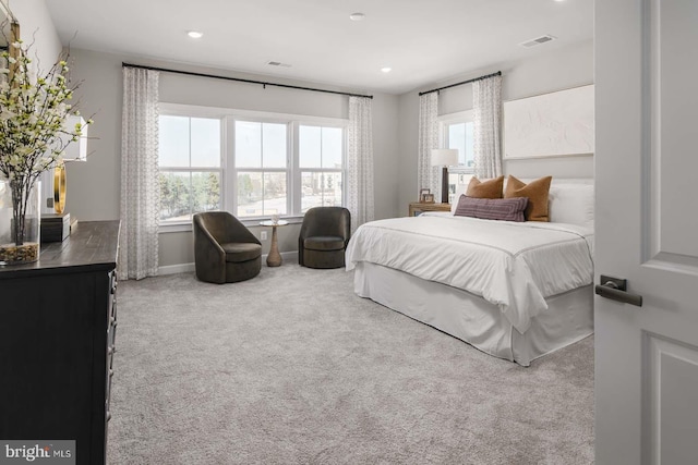 bedroom with carpet floors, visible vents, and multiple windows