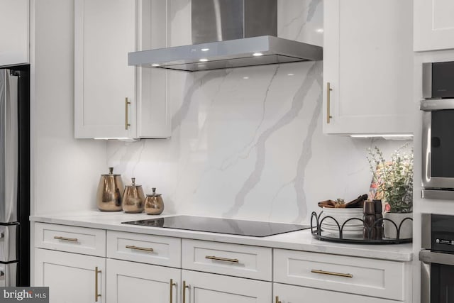 kitchen with wall chimney exhaust hood, decorative backsplash, white cabinets, and stainless steel appliances