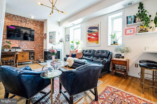 living room with visible vents, baseboards, a chandelier, a fireplace, and hardwood / wood-style flooring