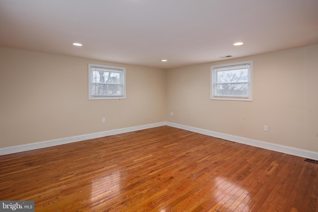 basement featuring plenty of natural light, baseboards, hardwood / wood-style floors, and recessed lighting