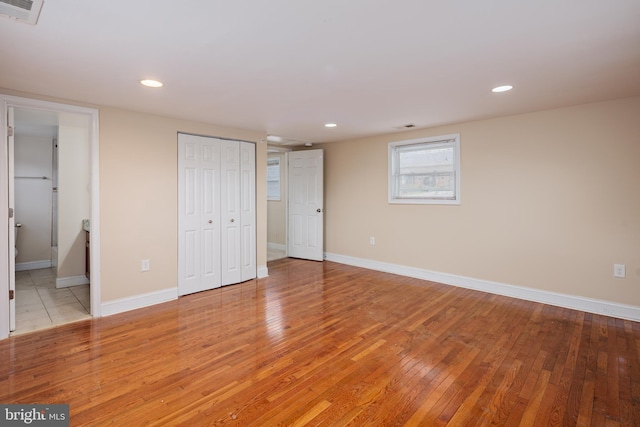 unfurnished bedroom with light wood finished floors, baseboards, visible vents, a closet, and recessed lighting