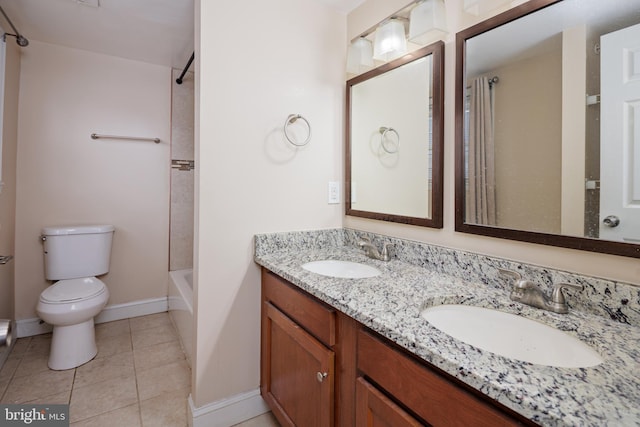 full bathroom featuring toilet, double vanity, a sink, and tile patterned floors