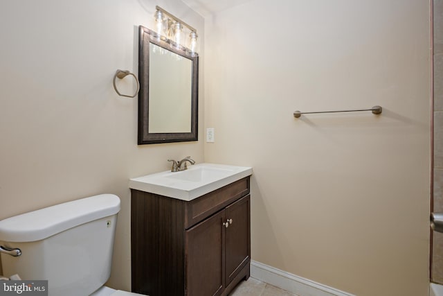 bathroom featuring toilet, vanity, and baseboards