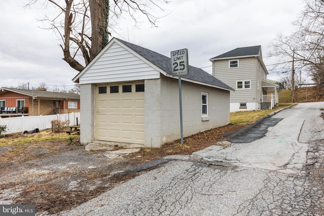 detached garage featuring driveway and fence