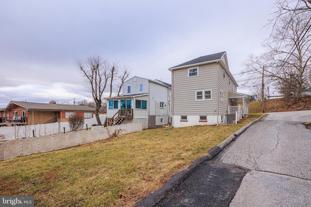 back of property with a lawn and fence