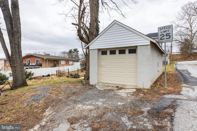 detached garage featuring driveway and fence