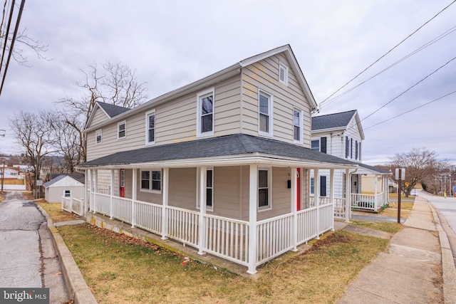 view of side of property with covered porch and roof with shingles