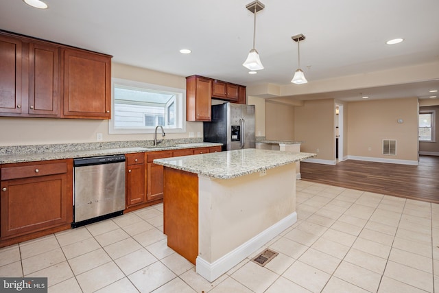 kitchen featuring light tile patterned floors, visible vents, a kitchen island, appliances with stainless steel finishes, and a sink