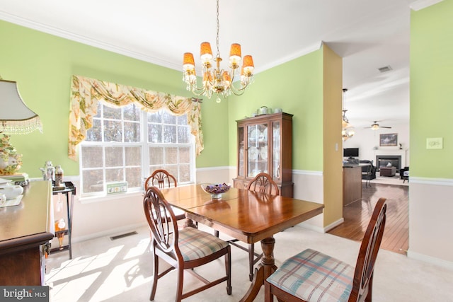 dining area with visible vents, ceiling fan with notable chandelier, a fireplace, and ornamental molding