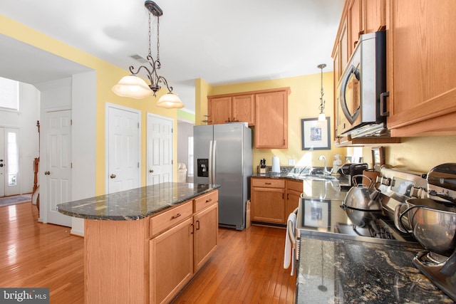 kitchen with visible vents, pendant lighting, a kitchen island, stainless steel appliances, and wood-type flooring