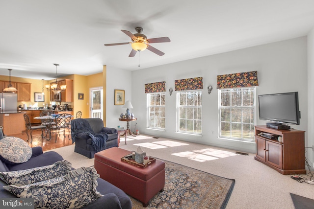 living room featuring light carpet and ceiling fan with notable chandelier