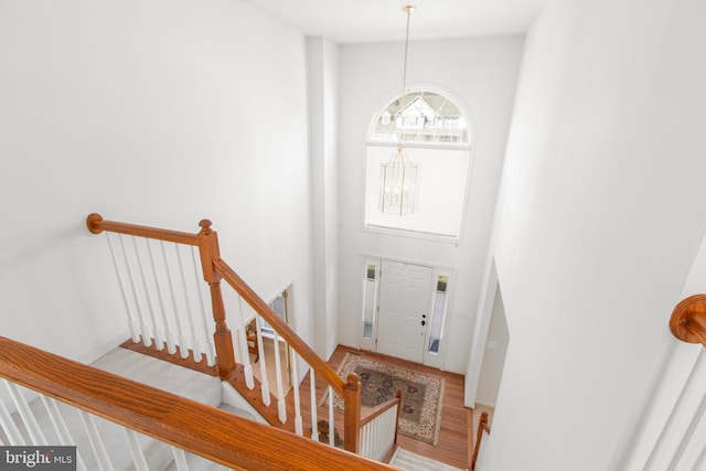 entryway with a chandelier, stairs, a towering ceiling, and wood finished floors