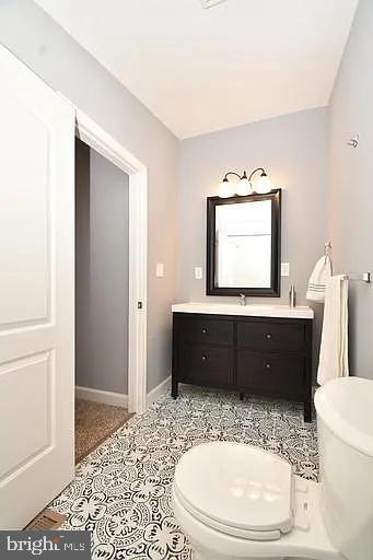 bathroom featuring toilet, tile patterned flooring, baseboards, and vanity