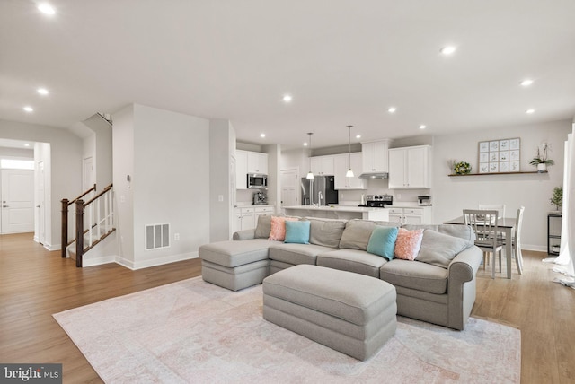 living area with light wood-type flooring, stairway, visible vents, and recessed lighting