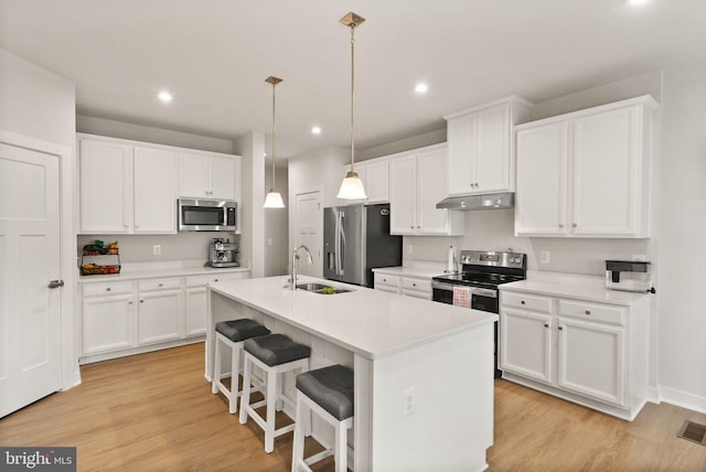 kitchen featuring appliances with stainless steel finishes, a sink, light wood-style flooring, and under cabinet range hood