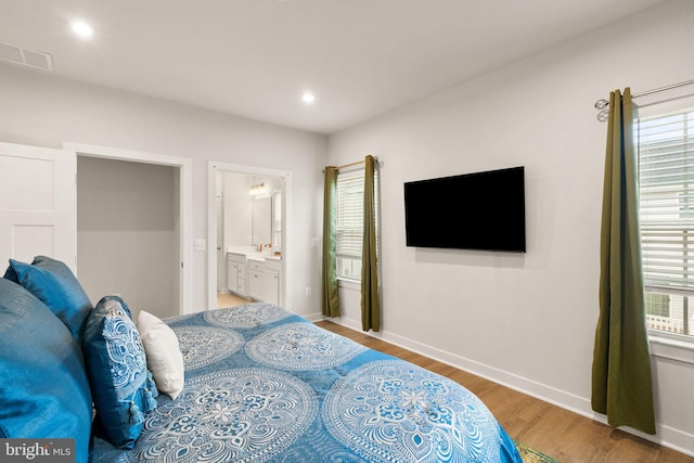 bedroom featuring visible vents, light wood-style flooring, baseboards, and ensuite bathroom