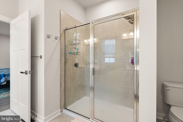 full bath with baseboards, a shower stall, and toilet