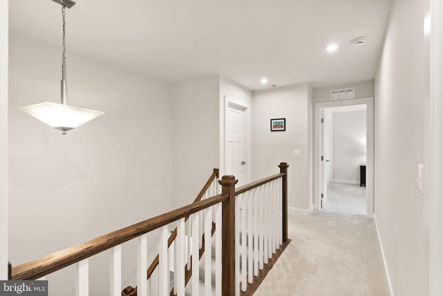 hall with recessed lighting, light colored carpet, visible vents, baseboards, and an upstairs landing