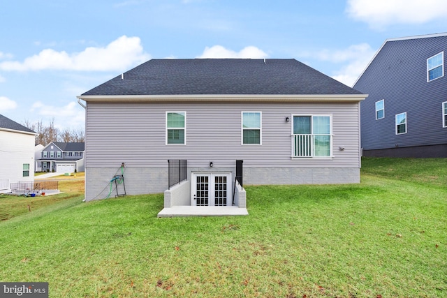 back of property featuring a shingled roof and a yard