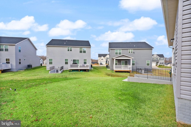 rear view of house featuring a lawn, a wooden deck, a residential view, and central air condition unit