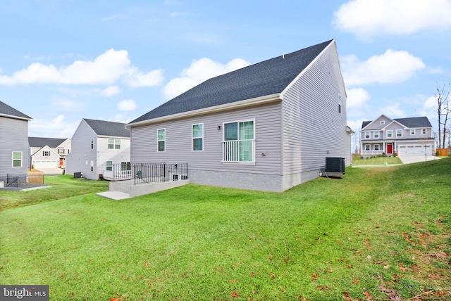 rear view of property featuring a residential view, central AC, and a lawn