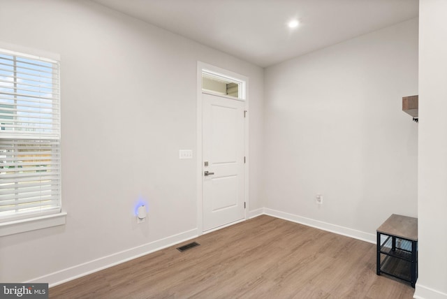 foyer entrance with light wood-type flooring, visible vents, and baseboards