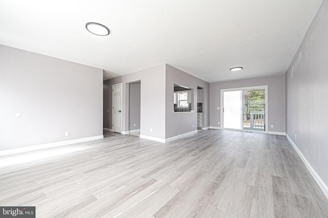 unfurnished living room featuring light wood-type flooring and baseboards