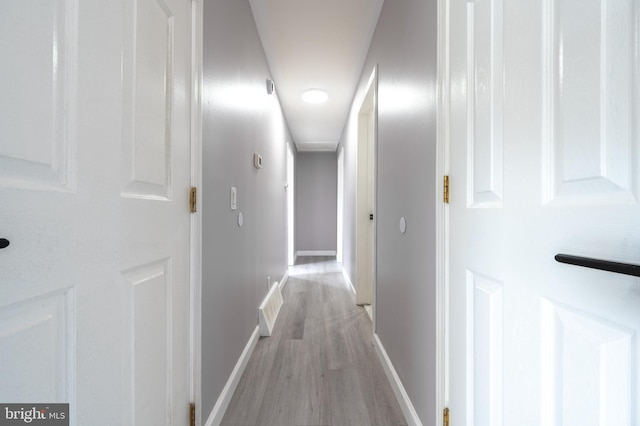 hall with light wood-type flooring and baseboards