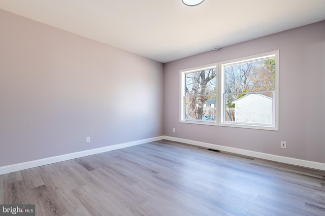 unfurnished room with visible vents, baseboards, and wood finished floors