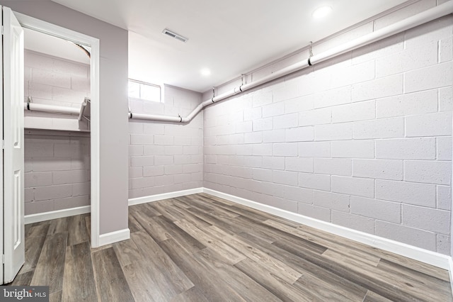 below grade area with recessed lighting, wood finished floors, visible vents, baseboards, and concrete block wall