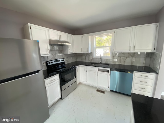 kitchen with dark countertops, appliances with stainless steel finishes, marble finish floor, under cabinet range hood, and a sink