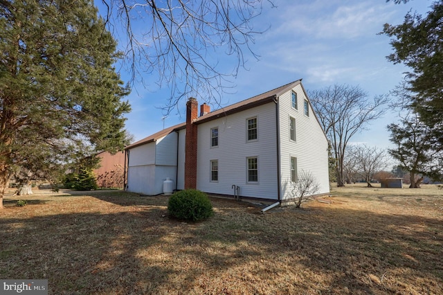 view of home's exterior with a chimney and a yard