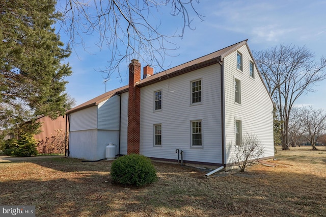 rear view of house with a chimney and a lawn